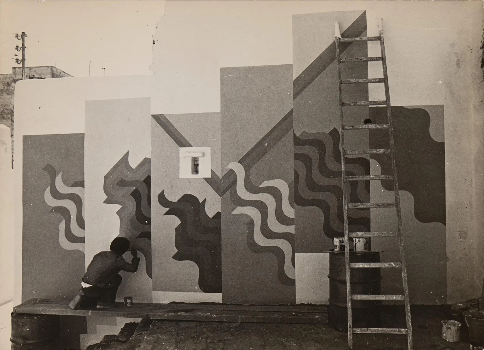 Painting a mural on a medina wall, ladder alongside